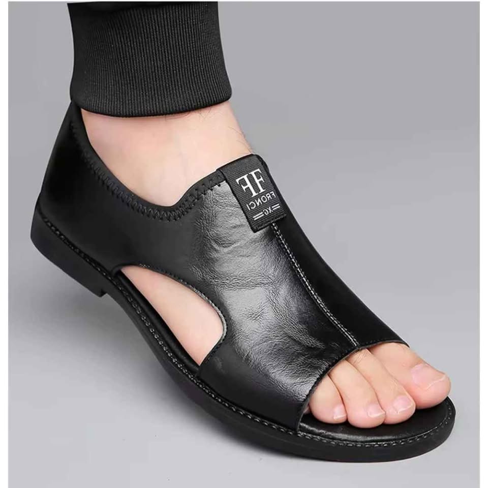 Gros plan d'une sandale homme premium en cuir souple noire portée au pied.